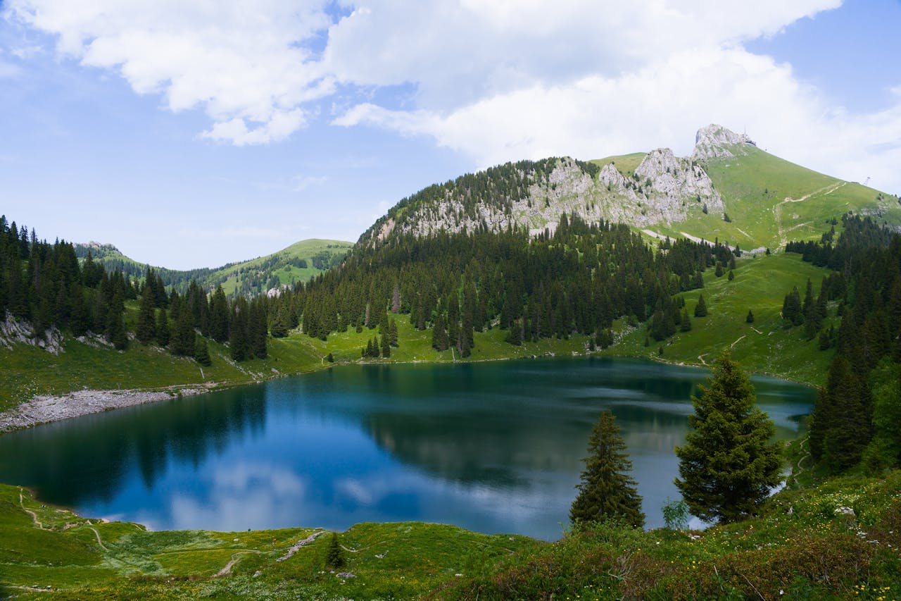 A serene landscape of a turquoise lake surrounded by lush green mountains in the Swiss Alps.